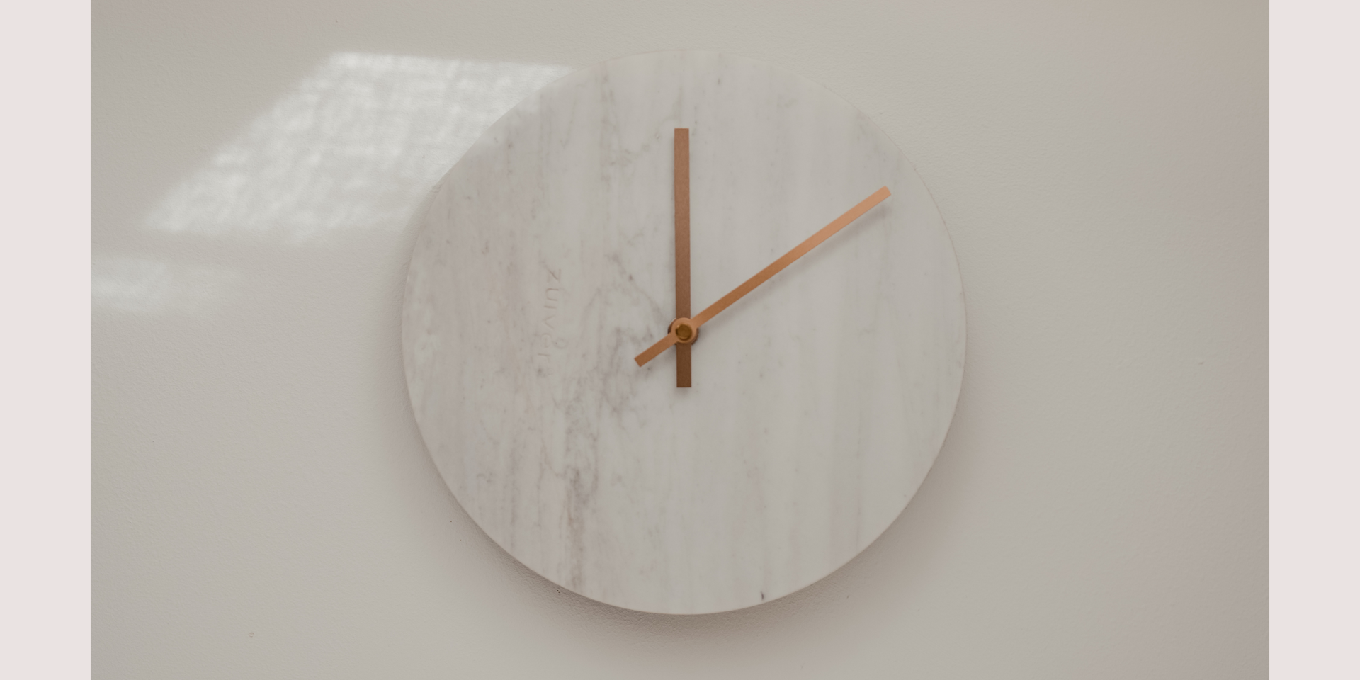 An hourglass sits on a desk next to a person using a laptop