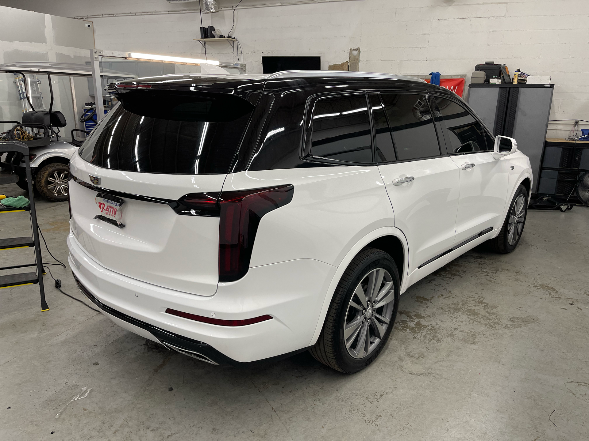 White Cadillac SUV with black roof and tinted windows parked indoors.