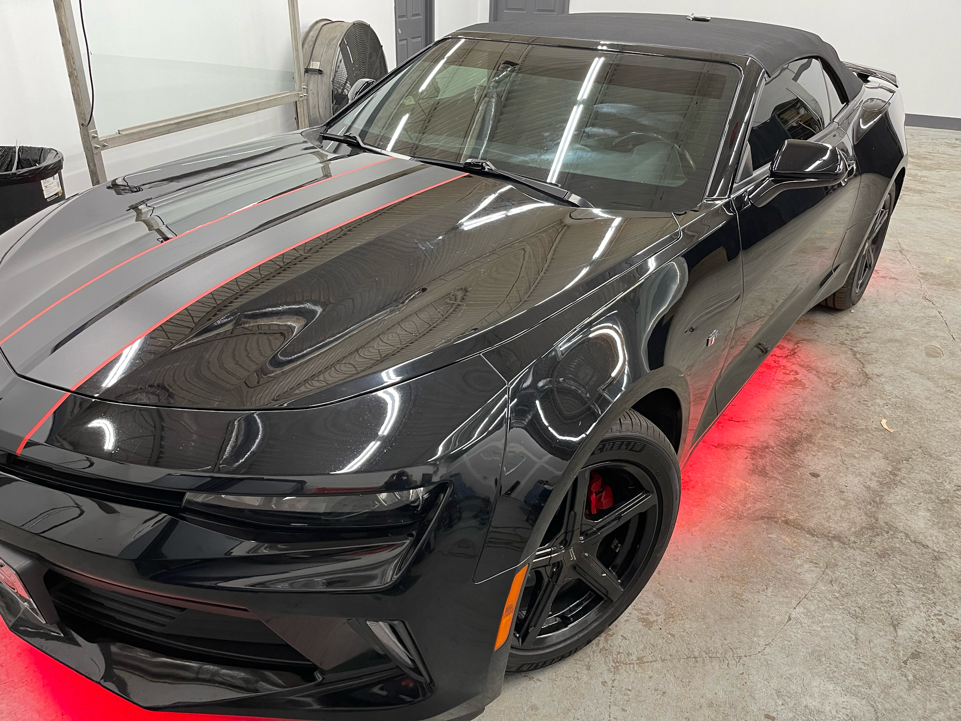 Black convertible Camaro with red accent lights and racing stripes.