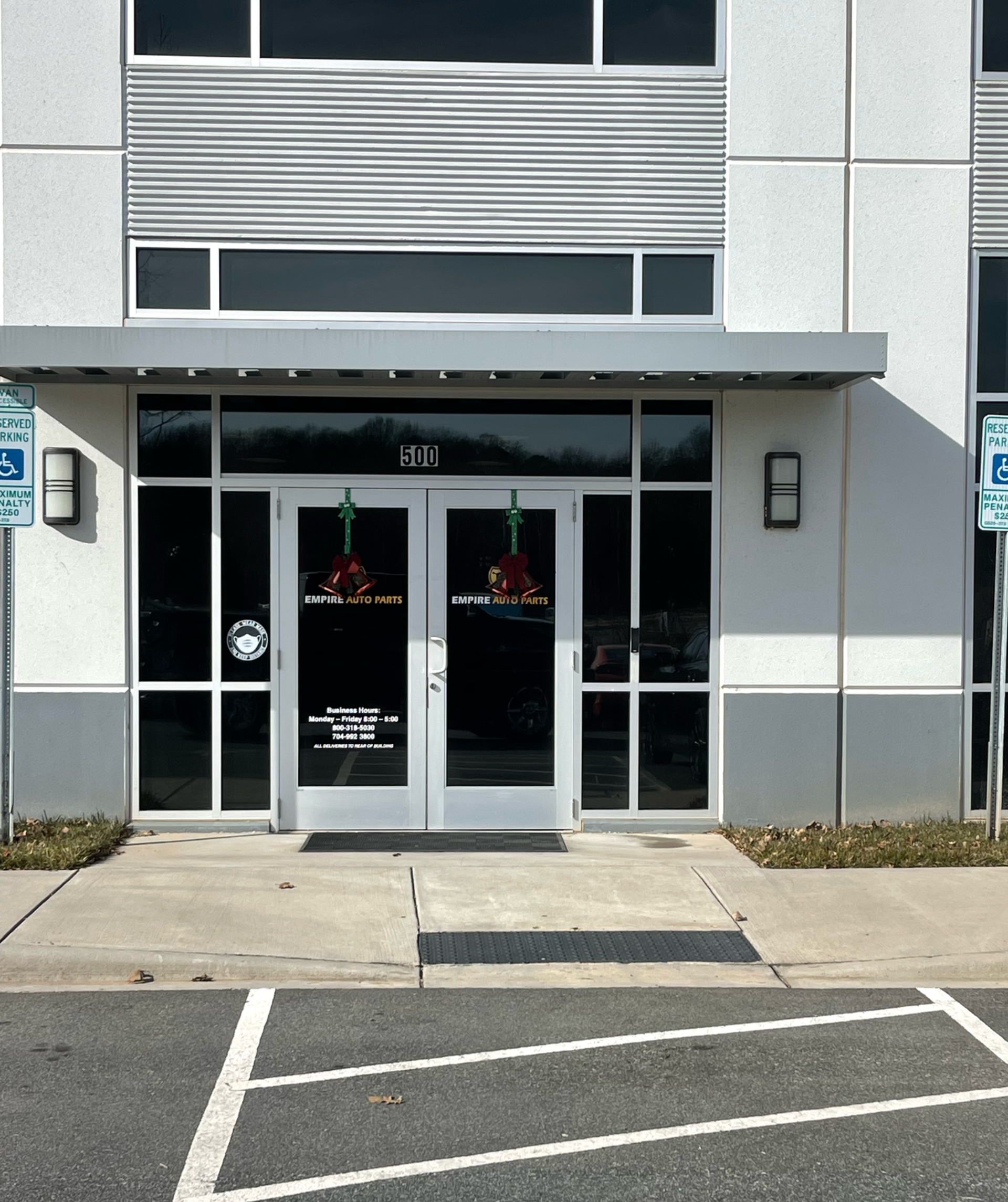 Exterior of a building with a glass entrance, accessible ramp, and two handicap parking spaces.