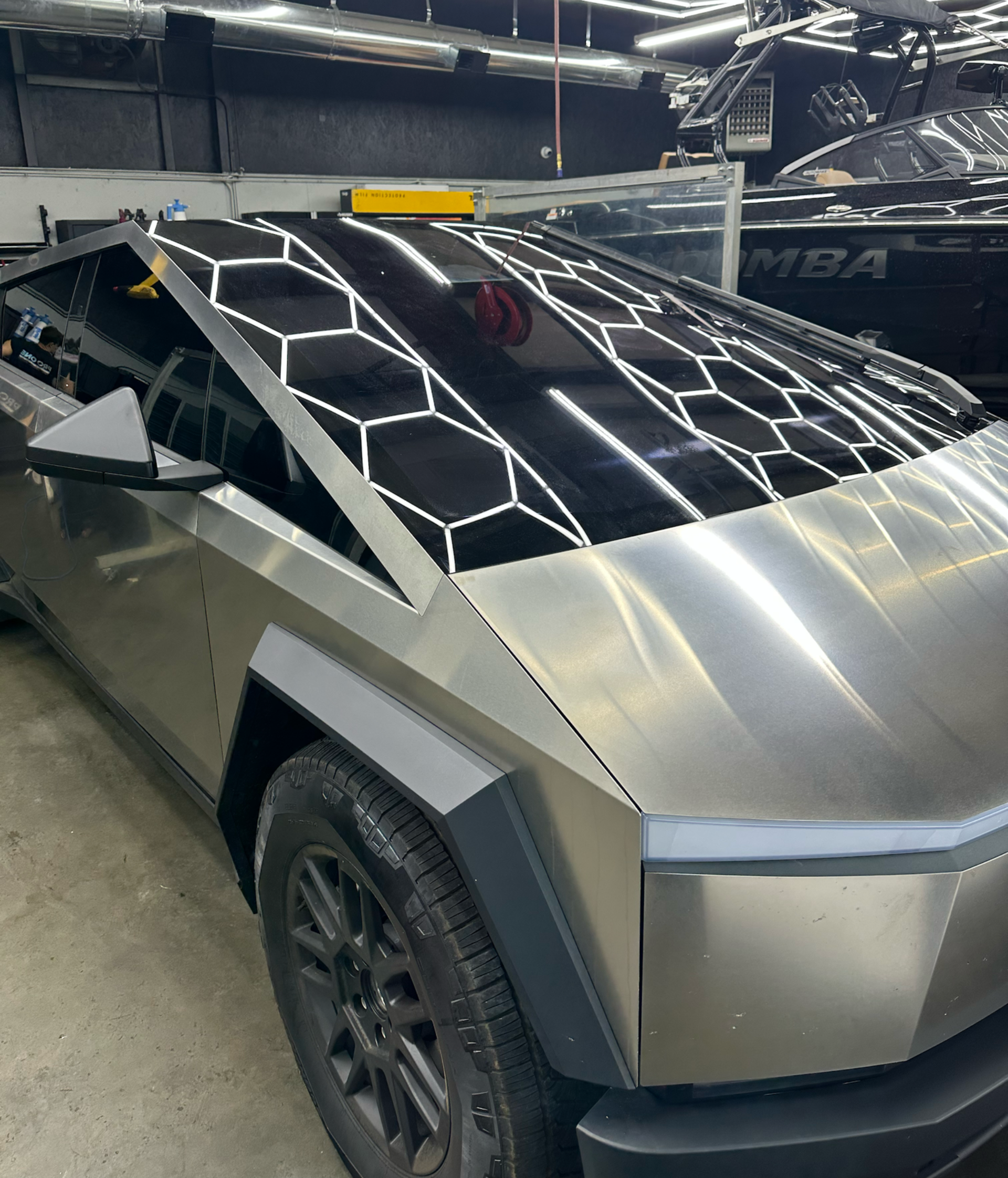 Tesla Cybertruck with custom honeycomb-patterned roof, metallic silver finish, parked indoors.