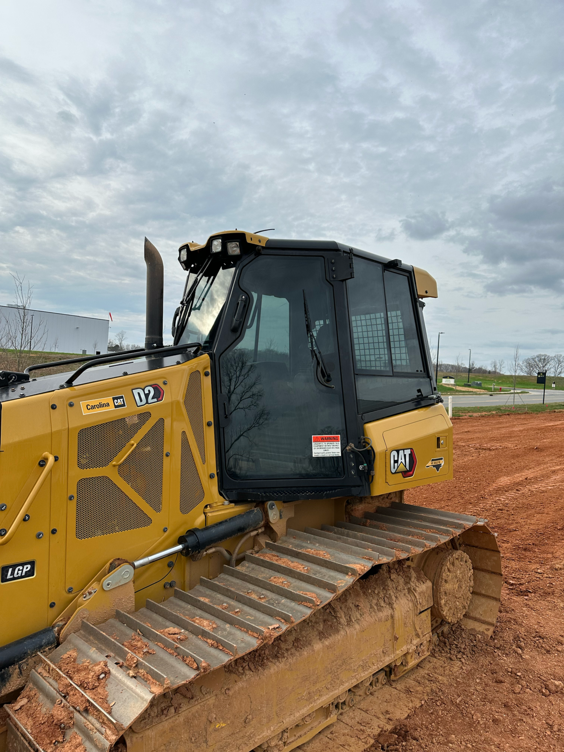 Yellow Caterpillar bulldozer on muddy ground under a cloudy sky.