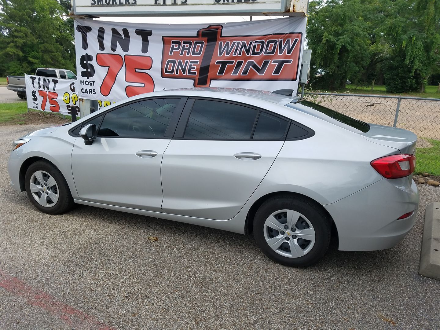 Silver car with tinted windows parked near a sign for 