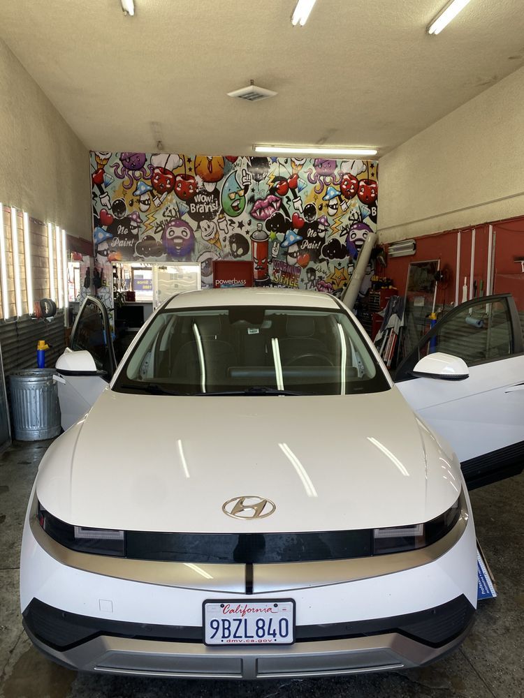 White Hyundai IONIQ 5 car inside a garage with open doors, cartoon mural in the background.