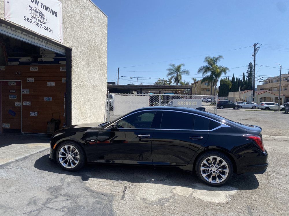 Black sedan with tinted windows parked outside a building labeled 