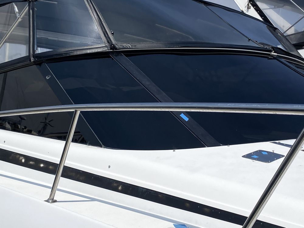 Boat's bow with stainless steel railing and dark-tinted windshield. Black trim on the white hull.