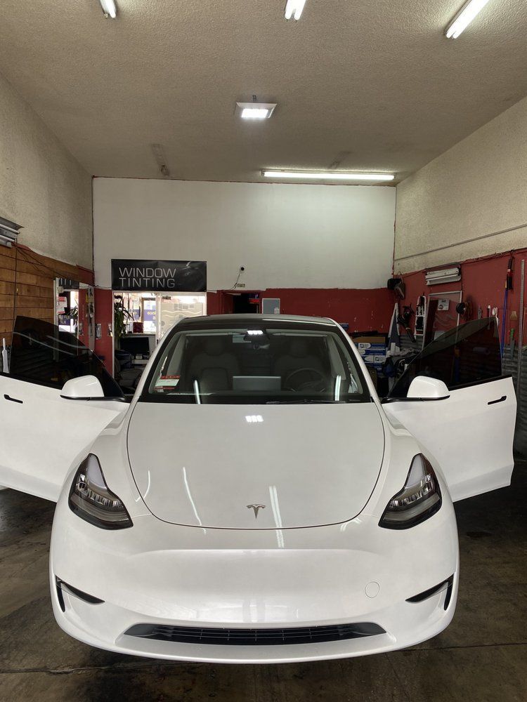 White Tesla car with open doors inside a garage, tinted windows.