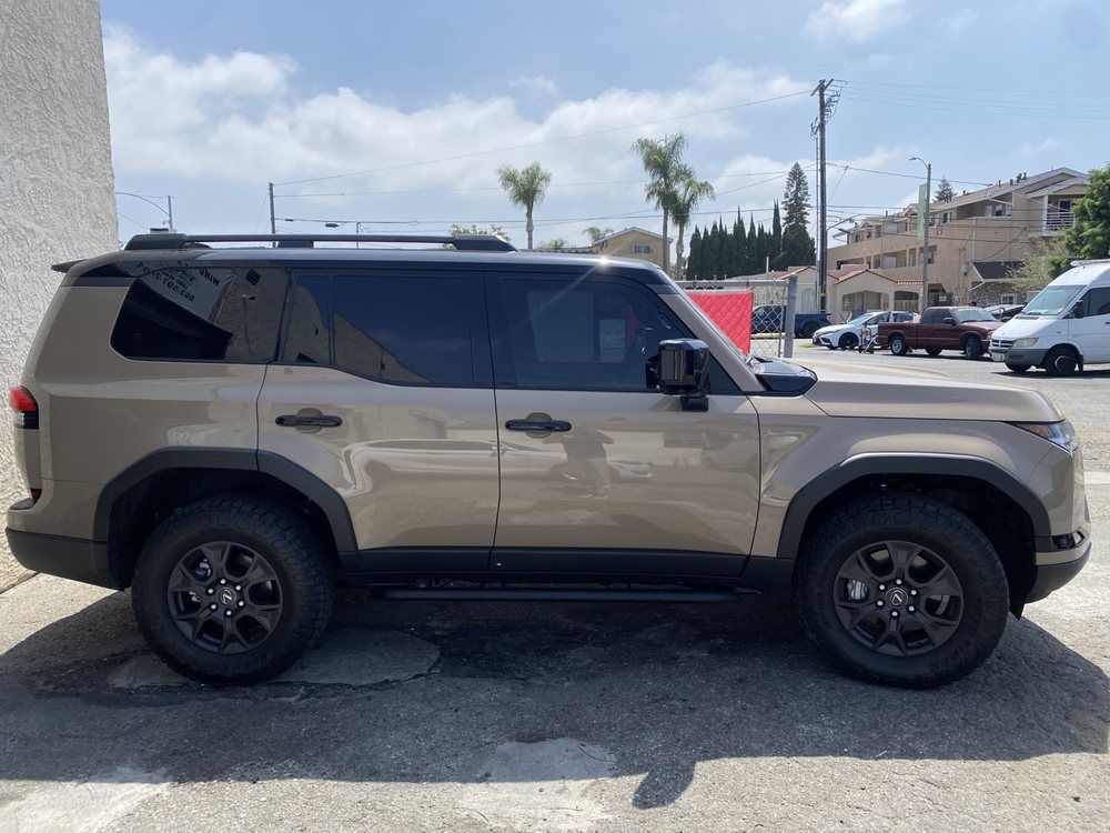 Tan SUV parked on asphalt. Black wheels, tinted windows. Sunny day, outdoor setting.