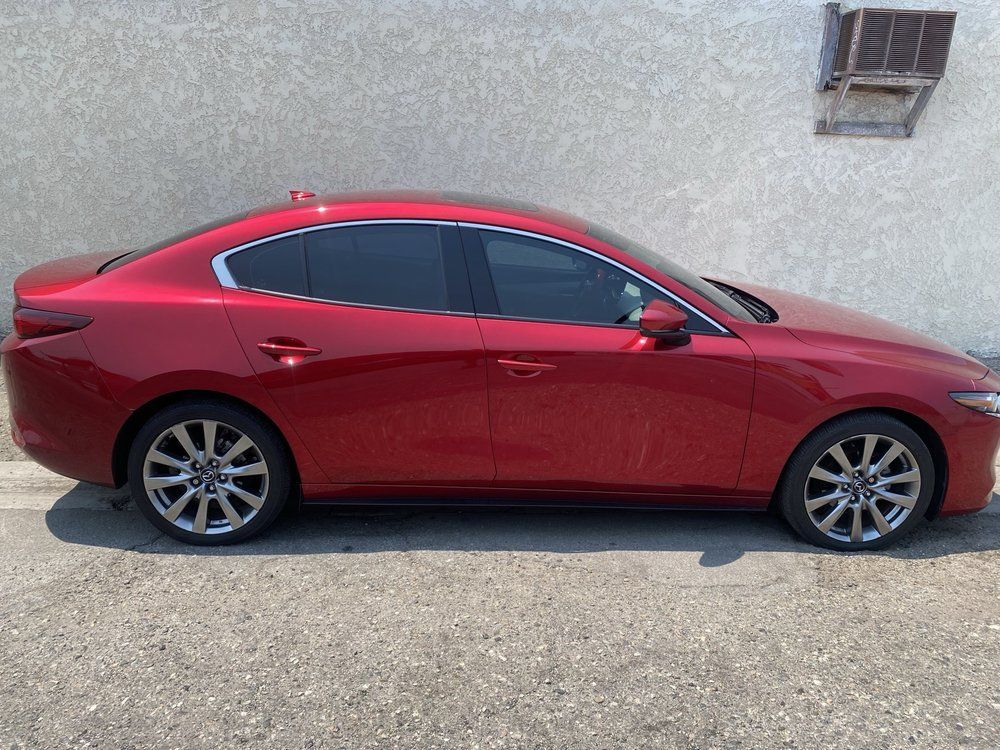 Red Mazda sedan parked next to a light-colored wall.