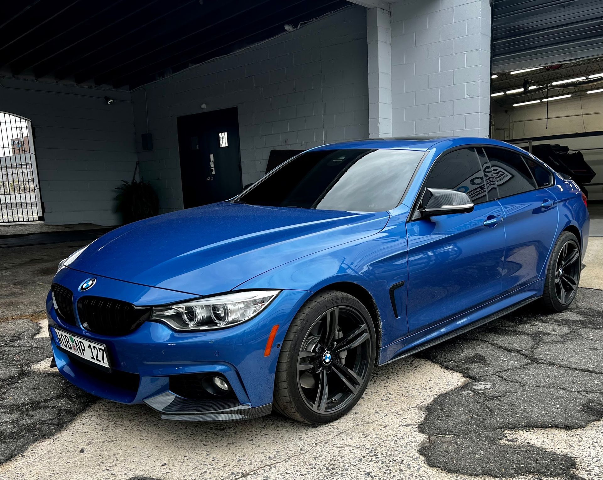 Blue BMW car parked under a structure with black wheels and tinted windows.
