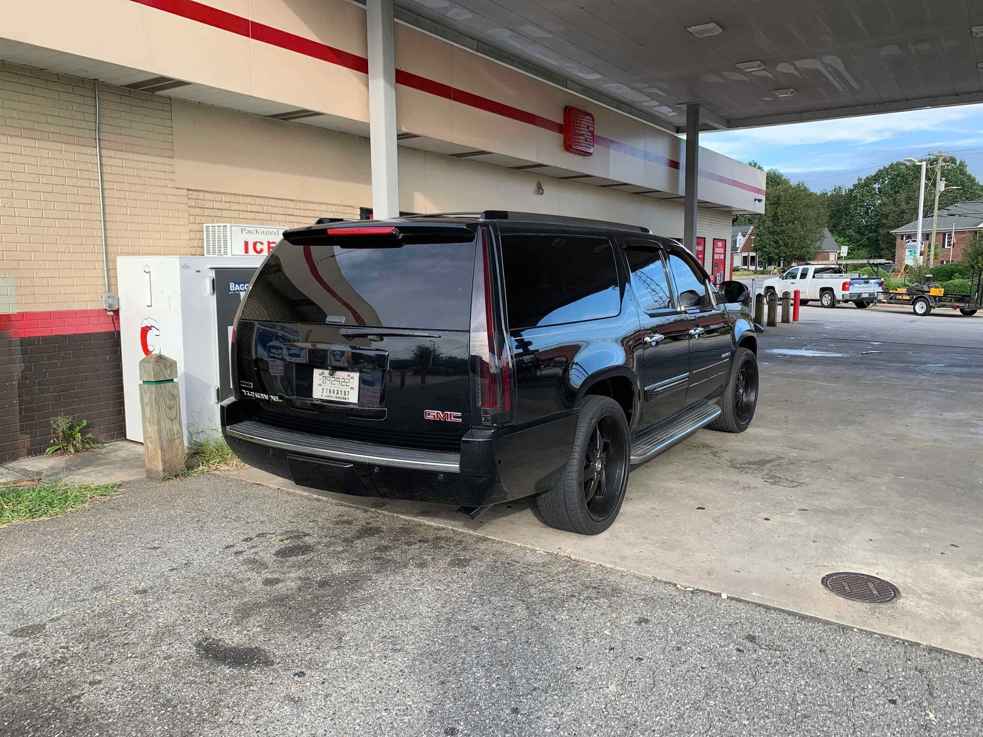 Black SUV parked at a gas station under a canopy; overcast sky.