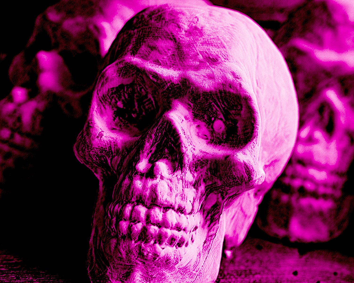 A purple skull is sitting on top of a pile of other skulls.