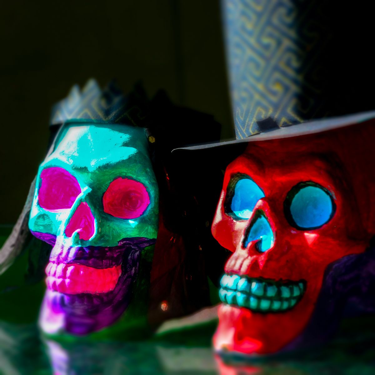 Two colorful skulls are sitting next to each other on a table