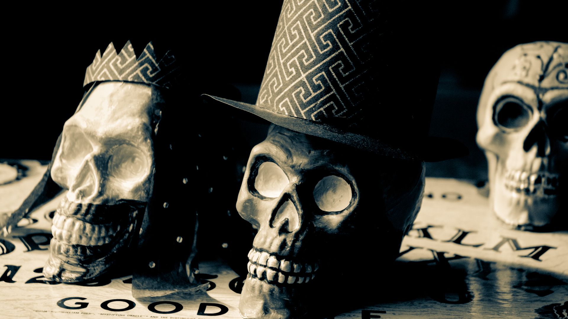 Three skulls wearing hats and crowns are sitting on a table.
