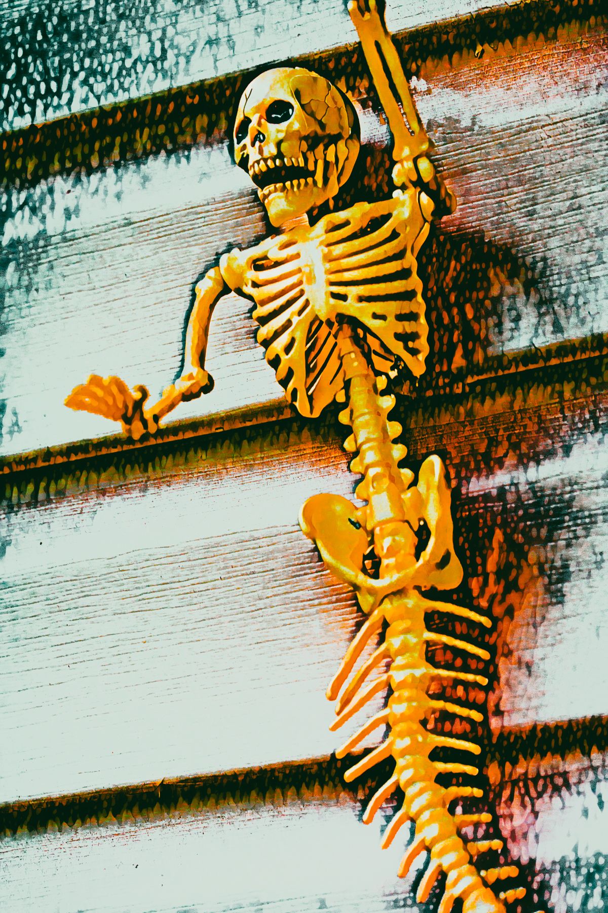 A yellow skeleton is hanging from a metal pole