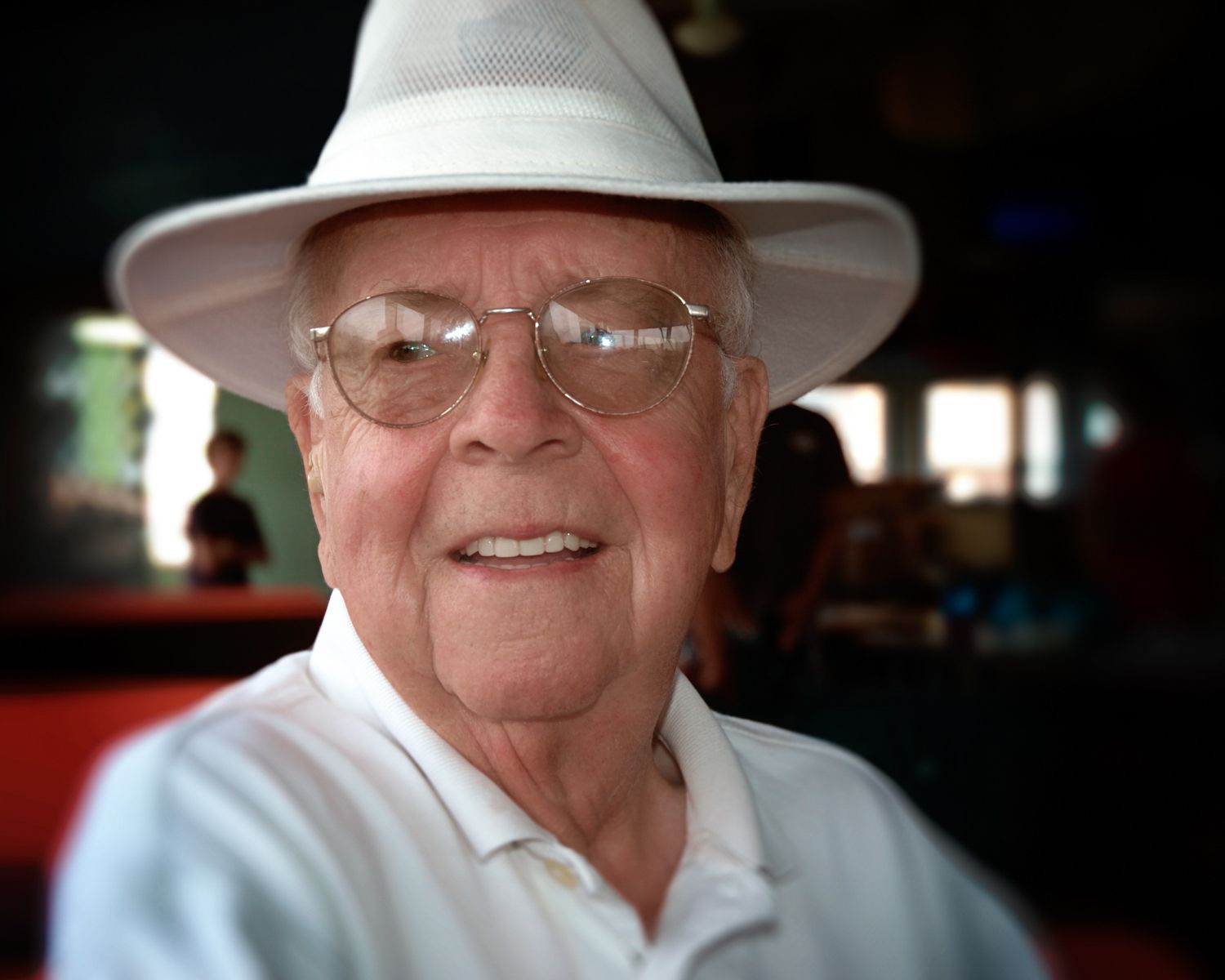 An elderly man wearing a white hat and glasses