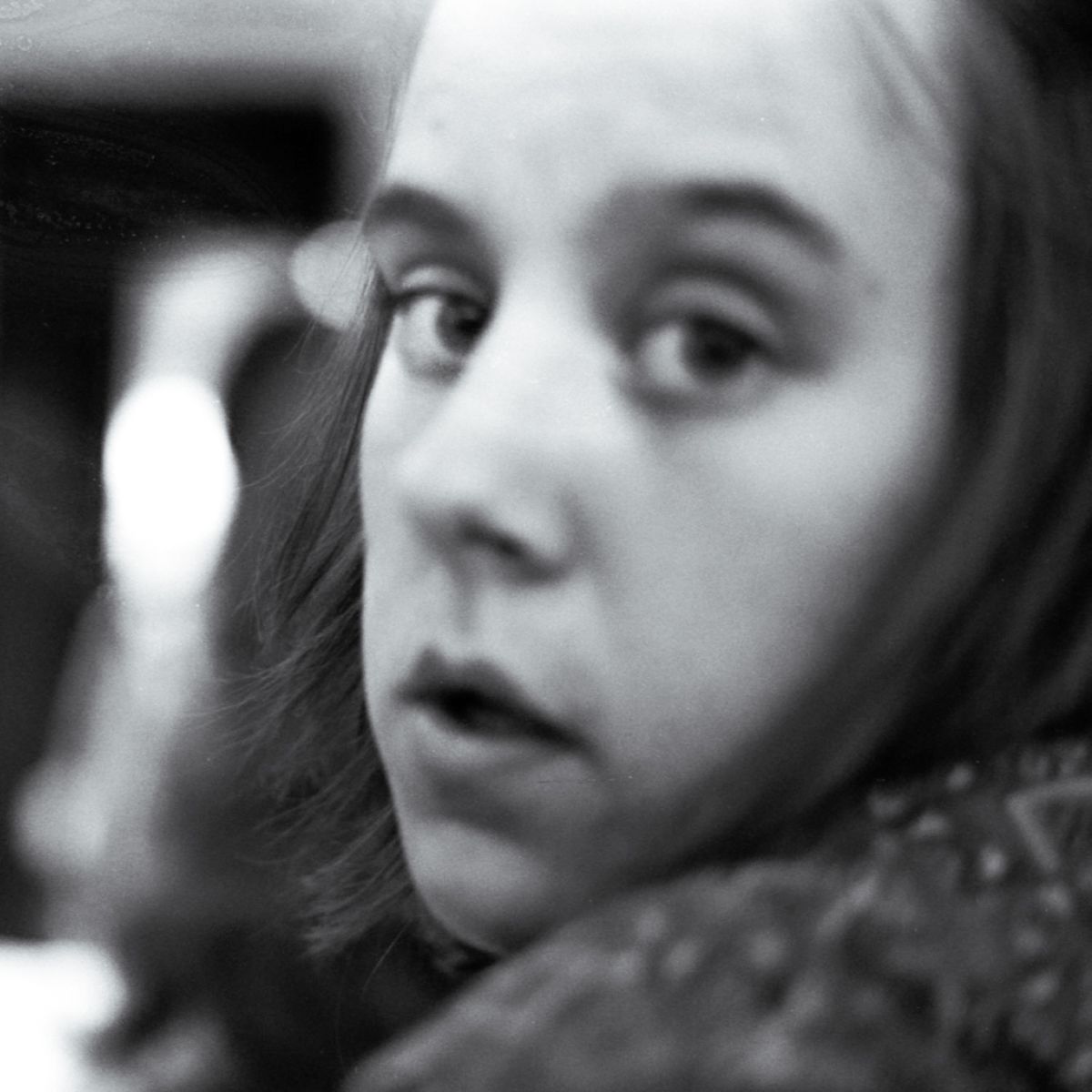 A black and white photo of a young girl looking at the camera.