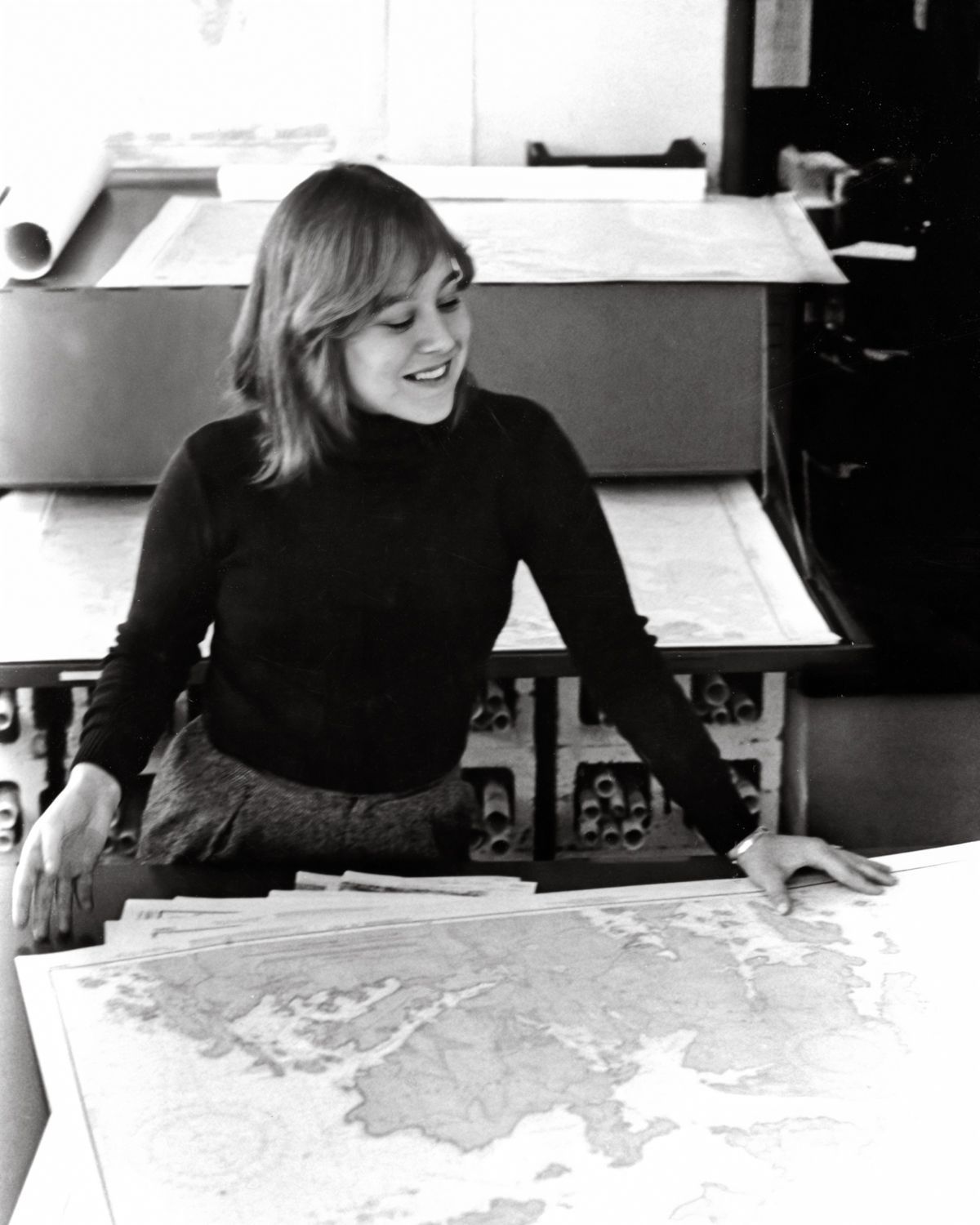 A black and white photo of a woman looking at a map