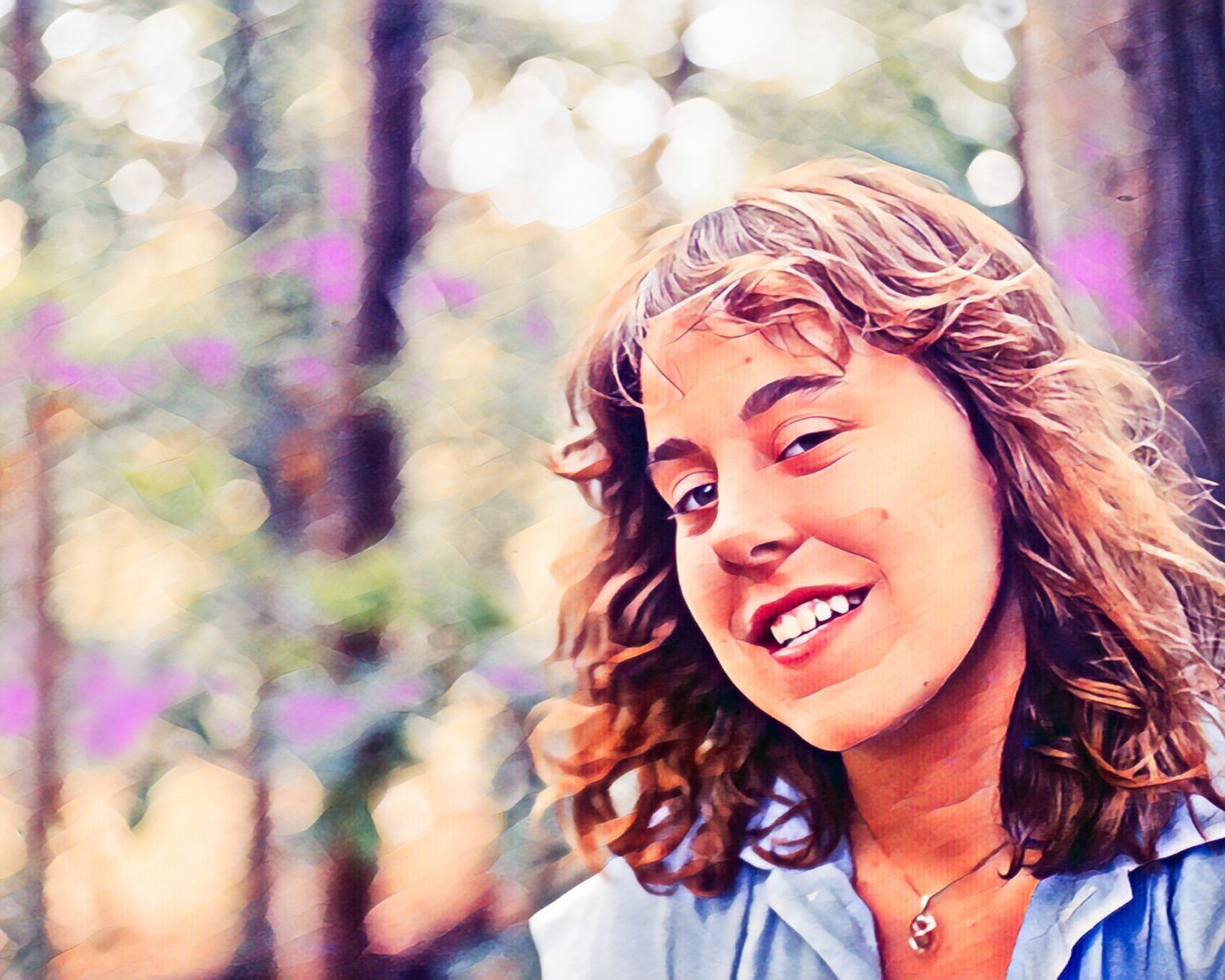 A woman wearing a blue shirt and a necklace smiles for the camera