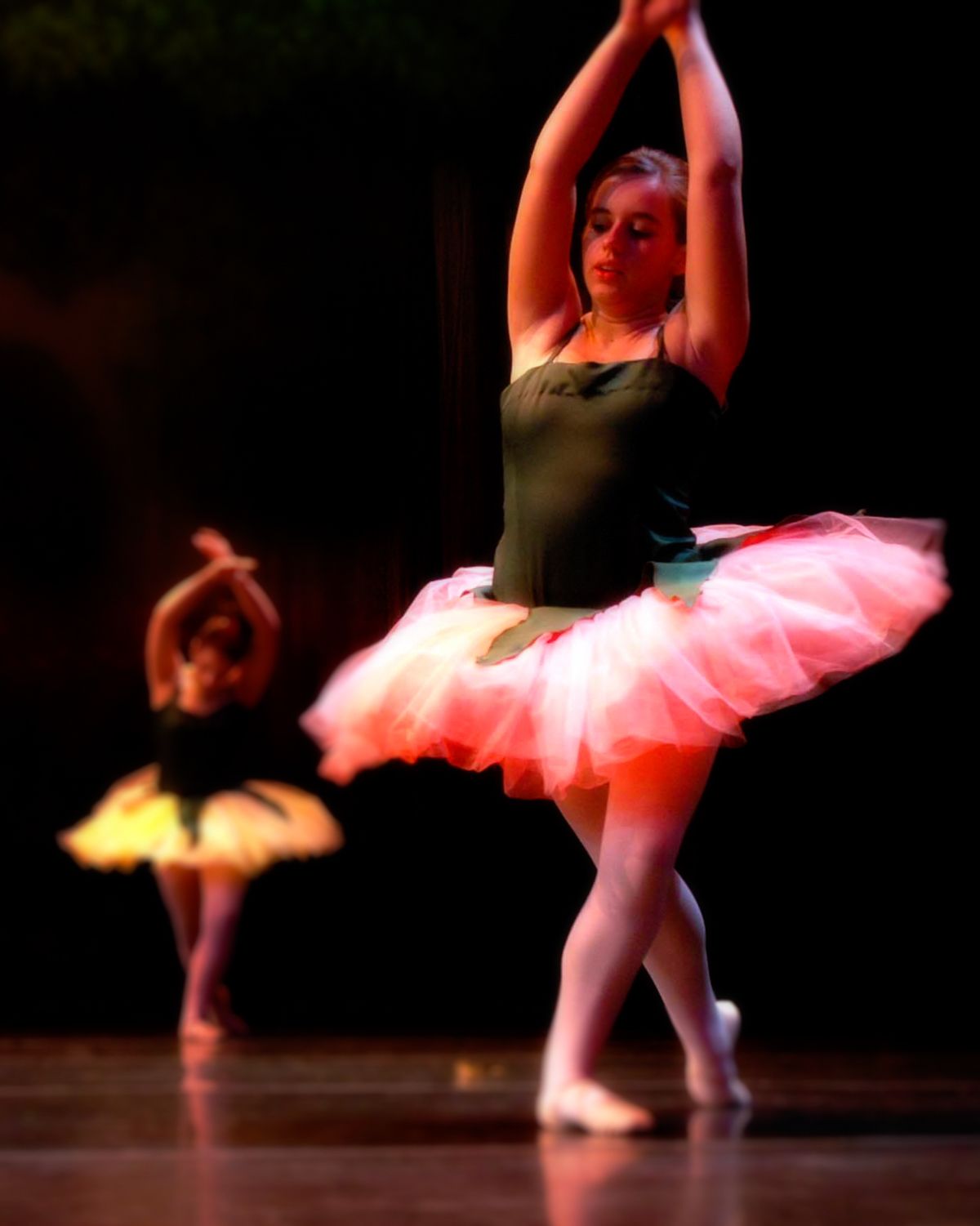 A woman in a pink tutu is dancing on a stage