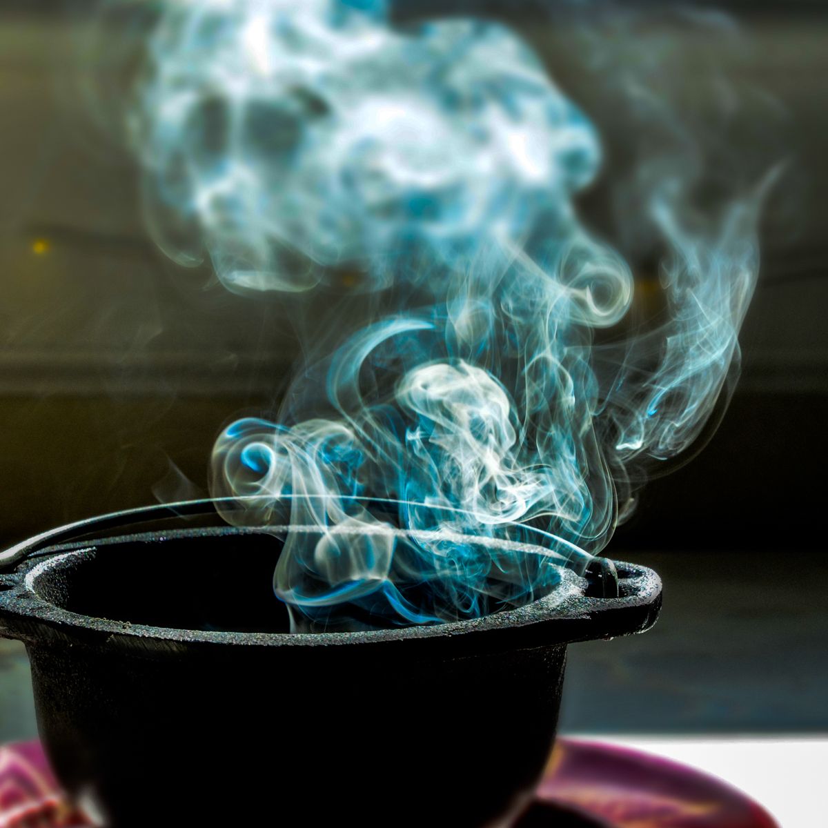 Smoke is coming out of a black pot on a saucer
