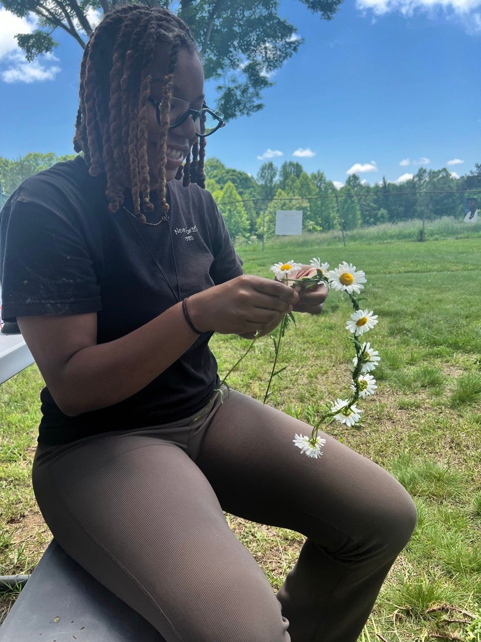A woman is sitting on a bench holding a flower crown