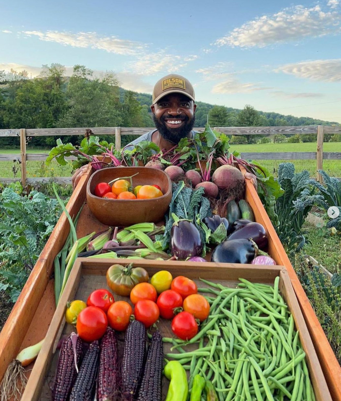 A man is sitting in a boat filled with vegetables.