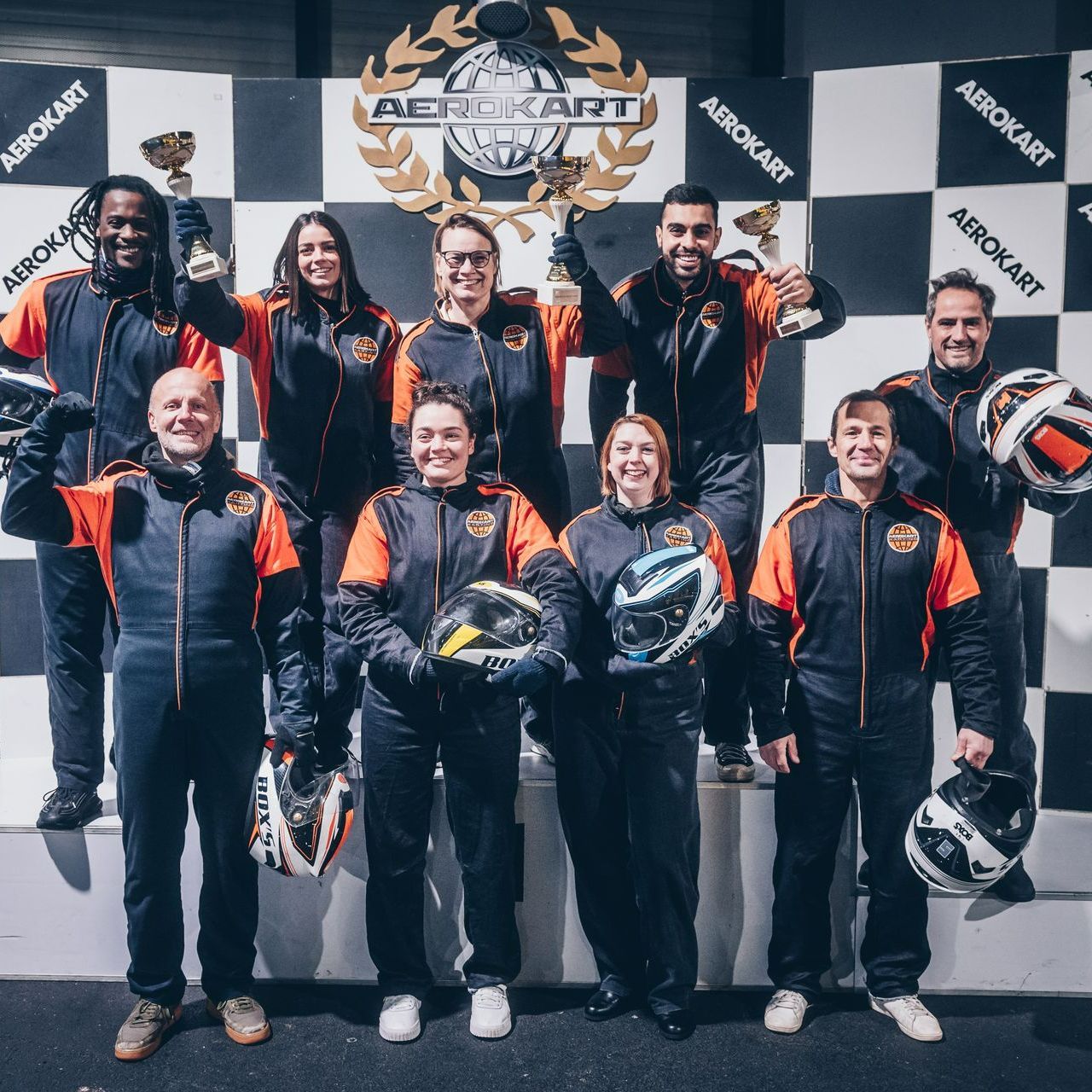 Une équipe de course de karting, tenant des trophées et des casques, se tiennent sur un podium avec écrit Aerokart.