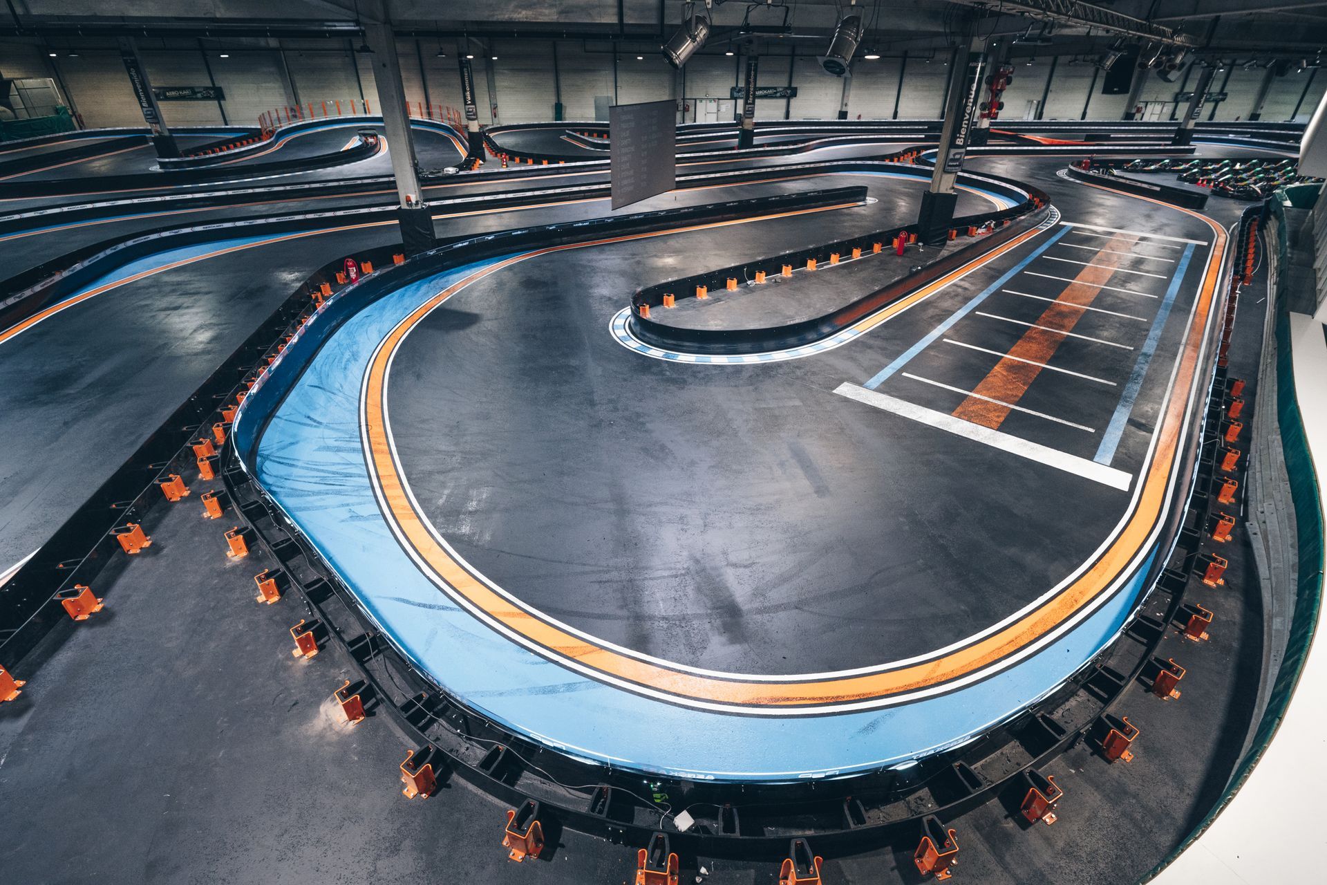 Indoor go-kart track with curved layout and safety barriers.