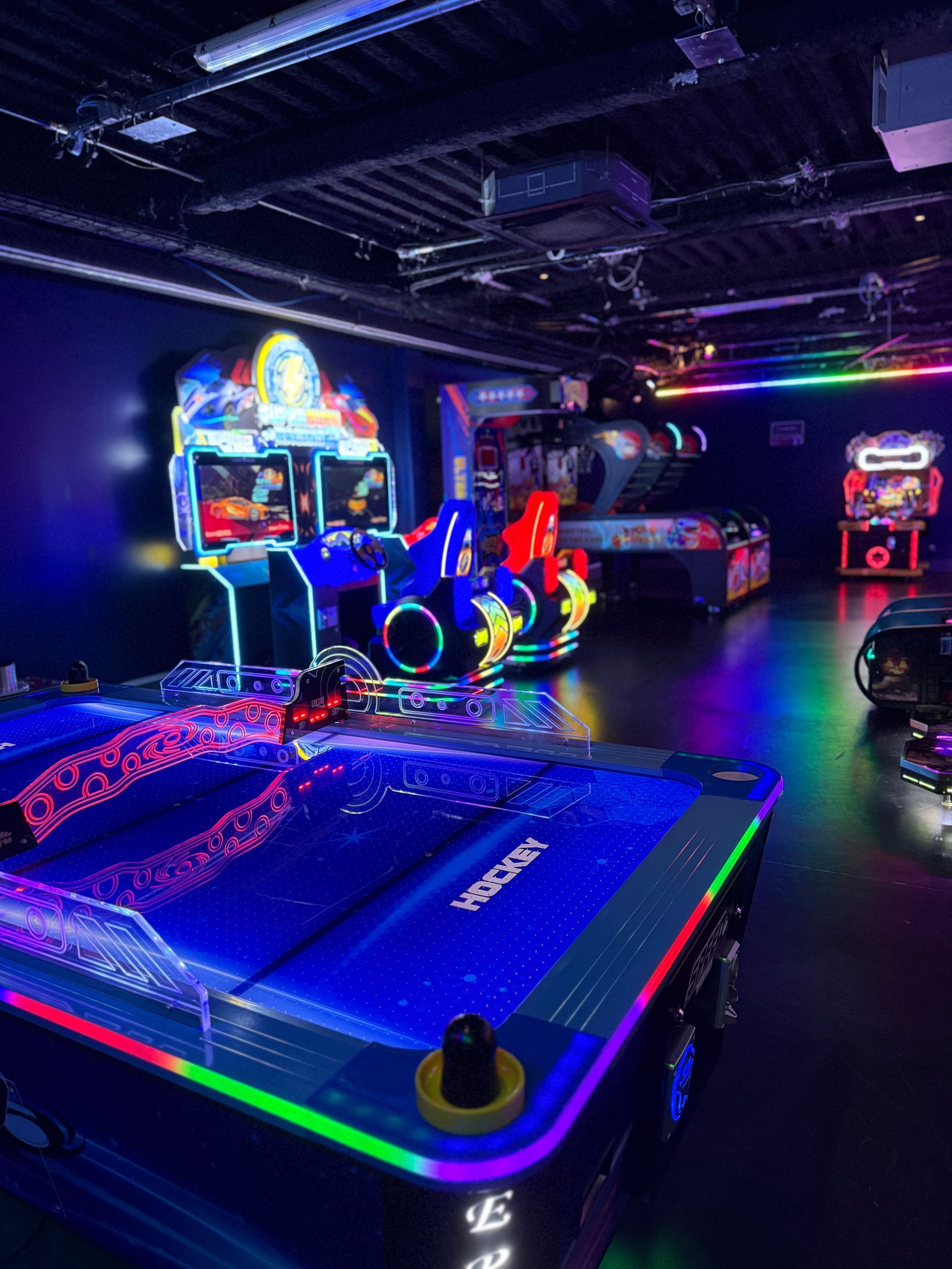 Des gens se sont rassemblés autour d'une table interactive lumineuse dans une pièce faiblement éclairée au néon.