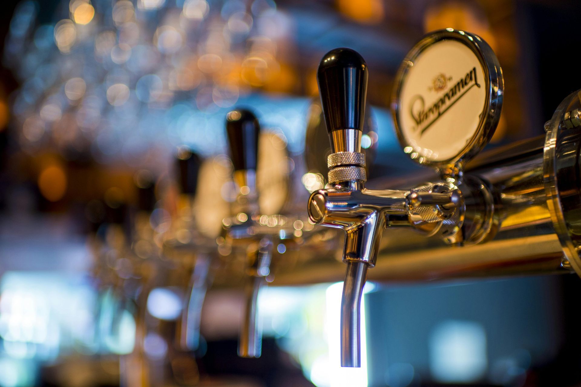 Gros plan de robinets à bière brillants avec un logo de marque sur un robinet, dans un pub.