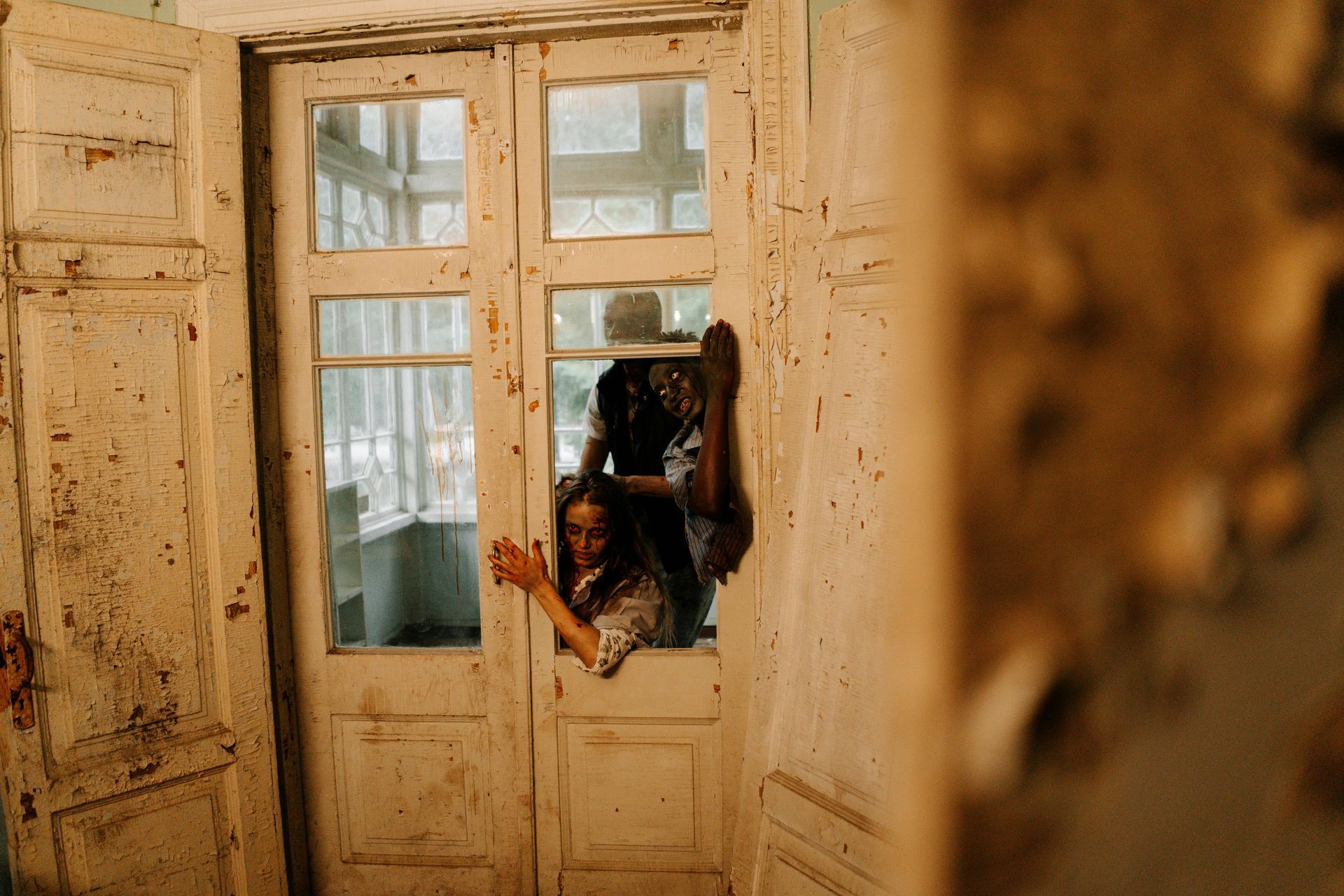 Une personne est coincée dans l'encadrement d'une porte. Une autre personne est partiellement visible derrière elle.