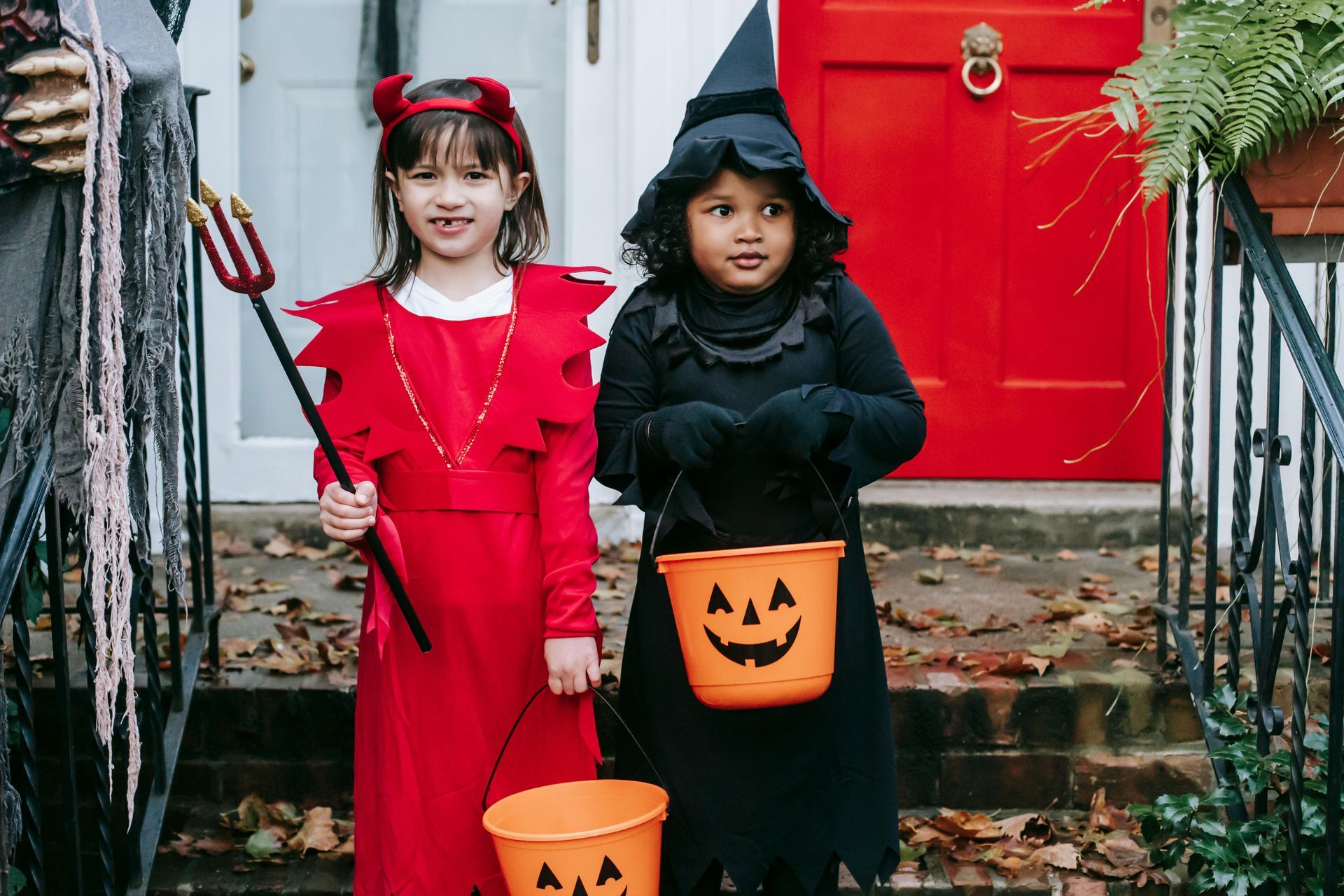Deux enfants déguisés pour Halloween sur un porche. L'un est déguisé en diable, l'autre en sorcière.