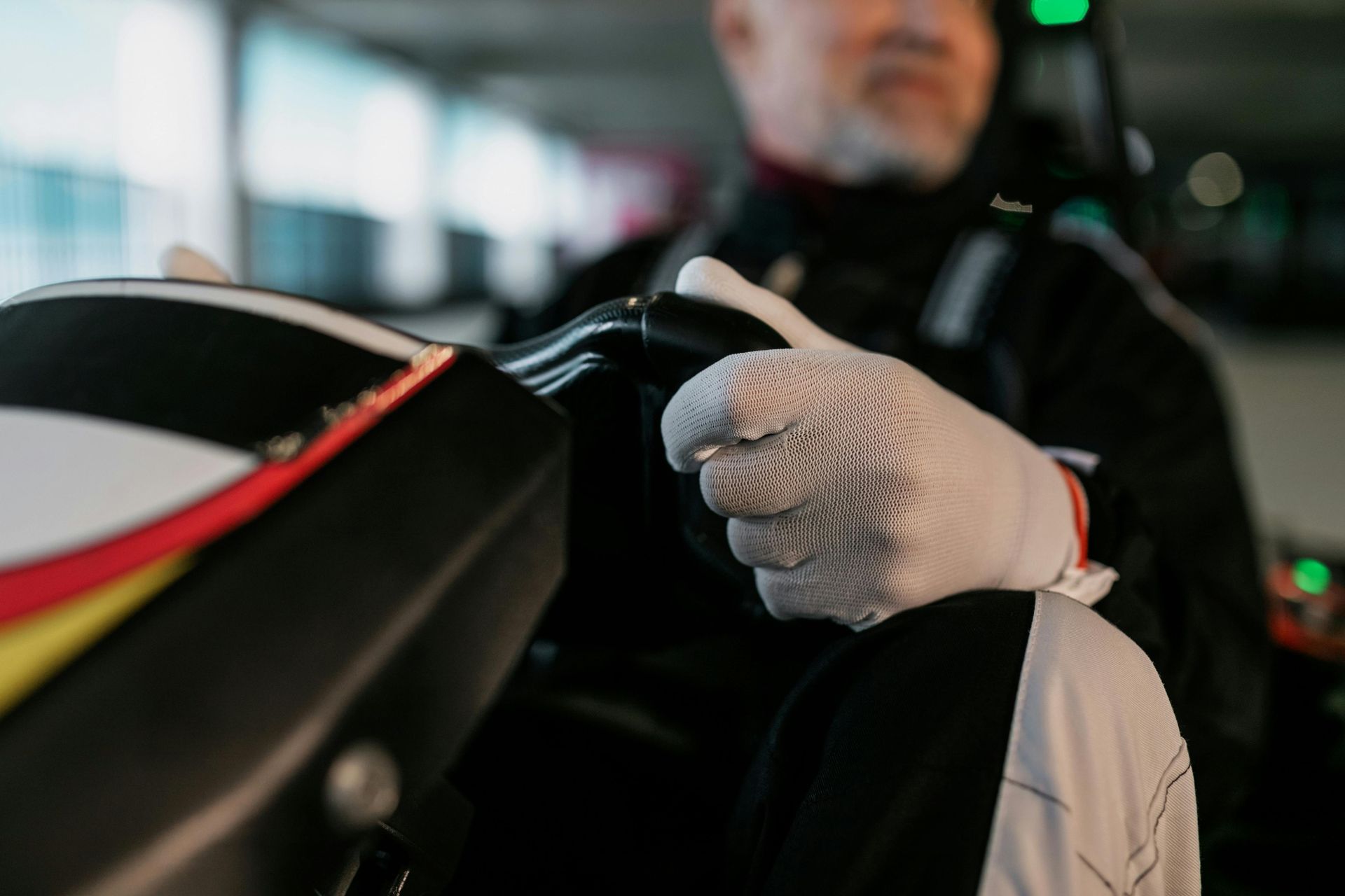 Personne tenant un volant noir de karting, portant des gants blancs.
