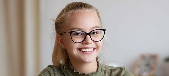 Smiling person with glasses, light hair pulled back, wearing a green shirt.