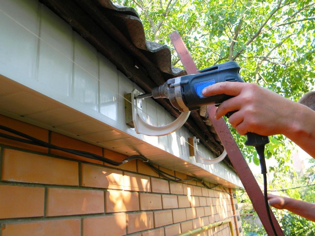 Worker using a circular saw on a roofline above a brick wall