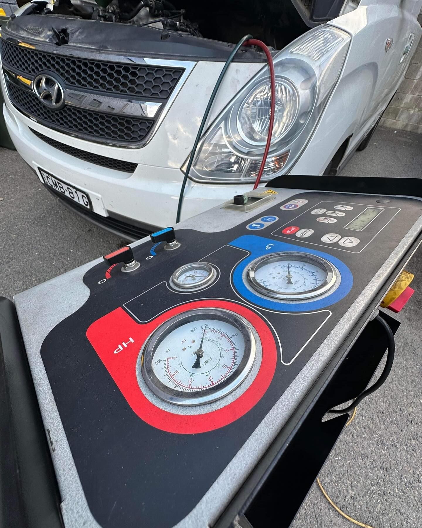Hands Attaching Blue and Red Pressure Gauges to a Car Engine — Nationwide Auto Service Centre in West Gosford, NSW