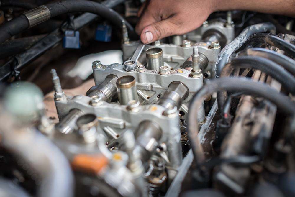 Hands Inspecting a Car Engine With Exposed Metal Components — Nationwide Auto Service Centre in West Gosford, NSW