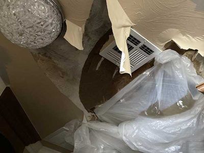 A person is standing in a room covered in plastic.