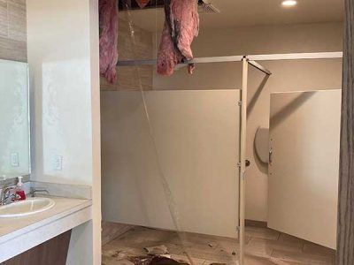 A bathroom with a sink , toilet and a broken ceiling.