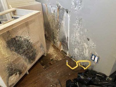 A laundry room with a dirty wall and a washer and dryer.