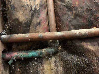 A close up of a copper pipe on a wooden wall.