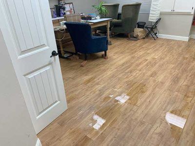 A room with a wooden floor , chairs , a table and a door.