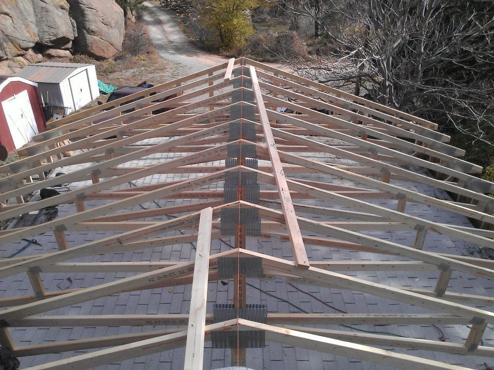 Roof trusses under construction, viewed along the ridge of a wooden roof frame.