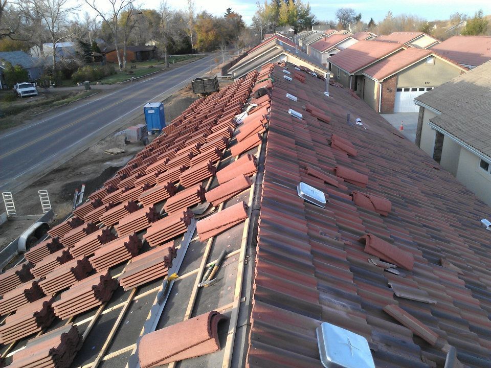 Rooftop with rows of red tiles beside a road and houses on a cloudy day