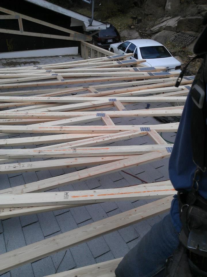 Collapsed wooden roof framing on a road, with a white car partly buried under debris near a tunnel entrance.