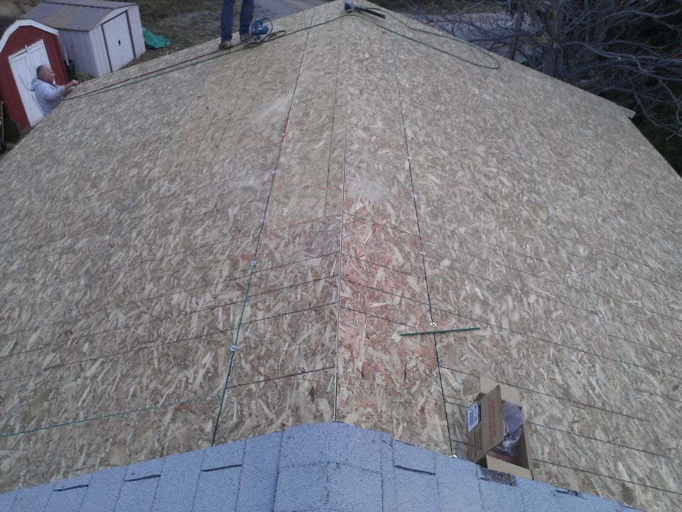 Roof under construction with OSB sheathing and workers visible at the top edge