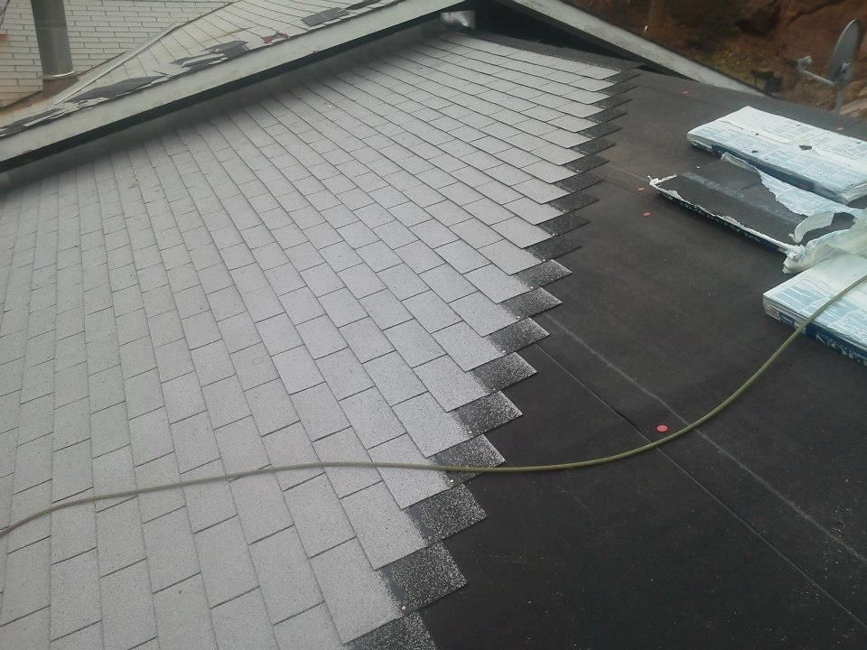 Roof repair with gray shingles and black underlayment exposed on a sloped roof