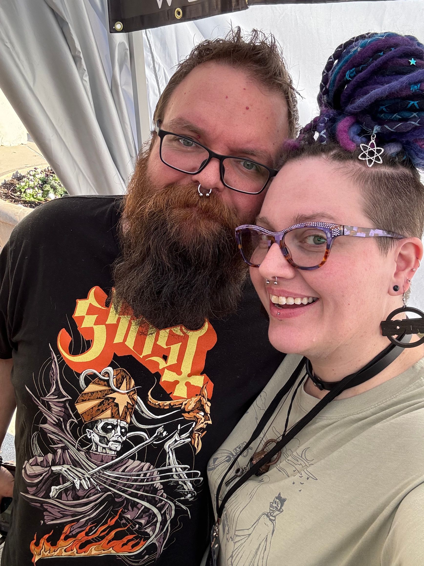 A man with a beard and a woman with dreadlocks are posing for a picture.
