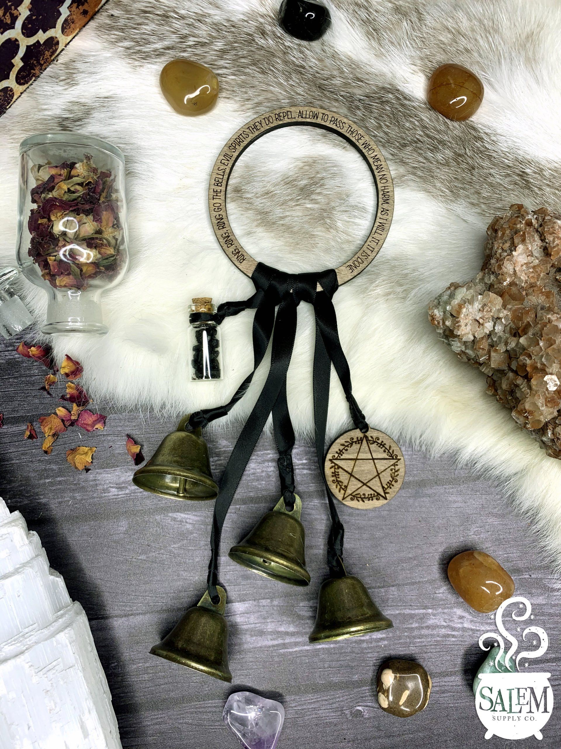A group of bells hanging from a ring on a table surrounded by crystals.